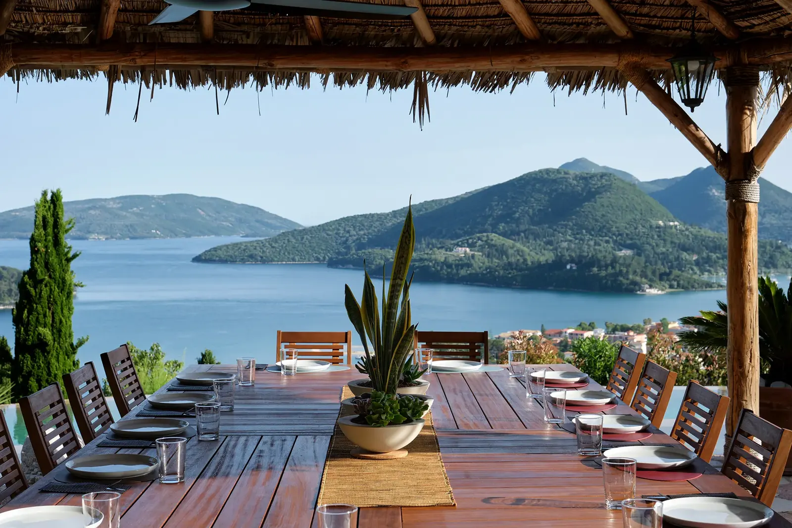 A long dining table set on the terrace above the sea